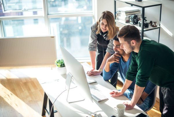 Three coworkers looking at computer in the office