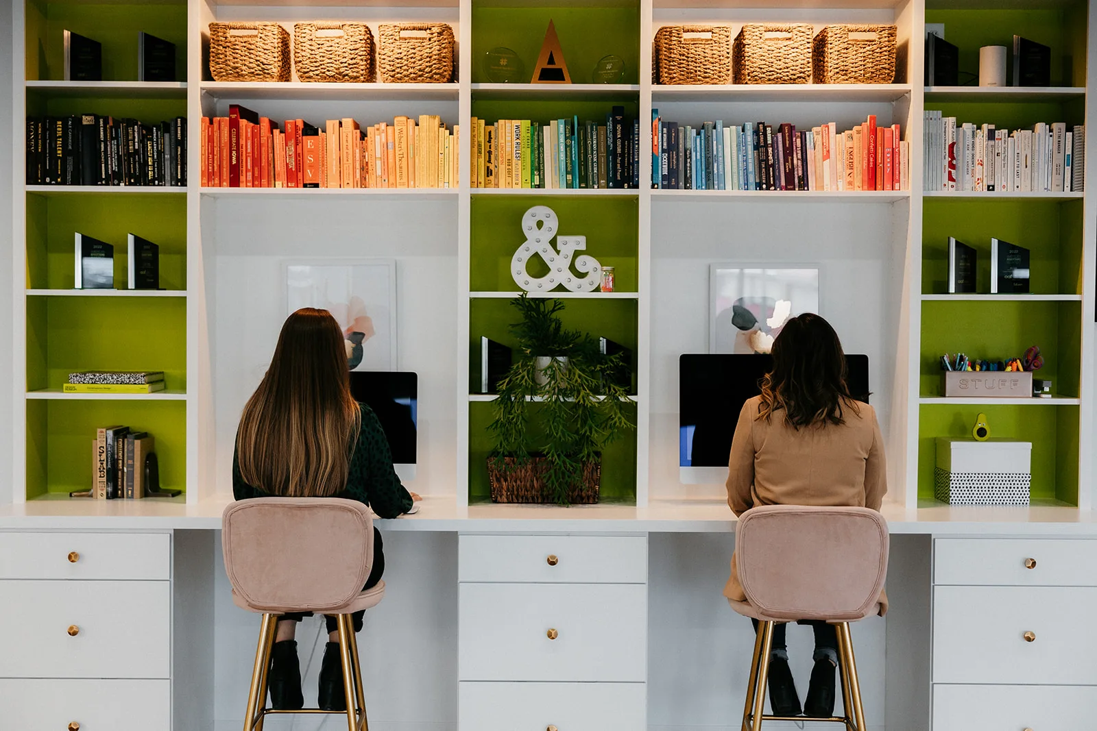 Bookshelves and workspace at TwoTone Creative, showcasing a library and team members reading.