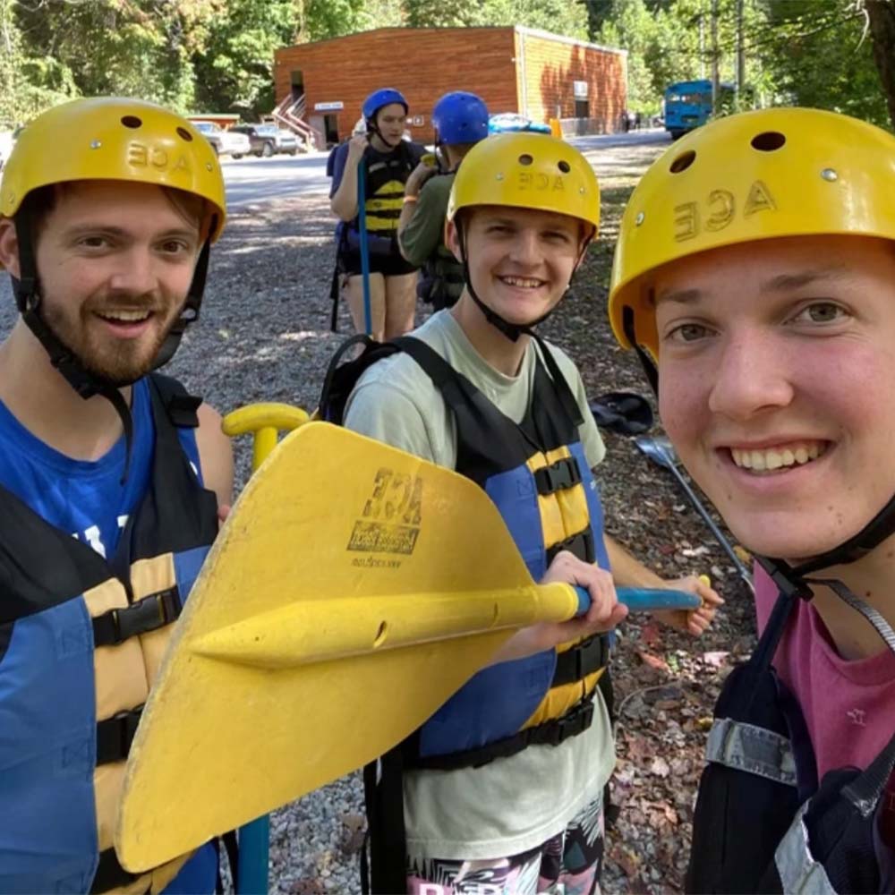Jackson Adams and TwoTone Creative team members wearing yellow helmets and life vests, holding paddles.
