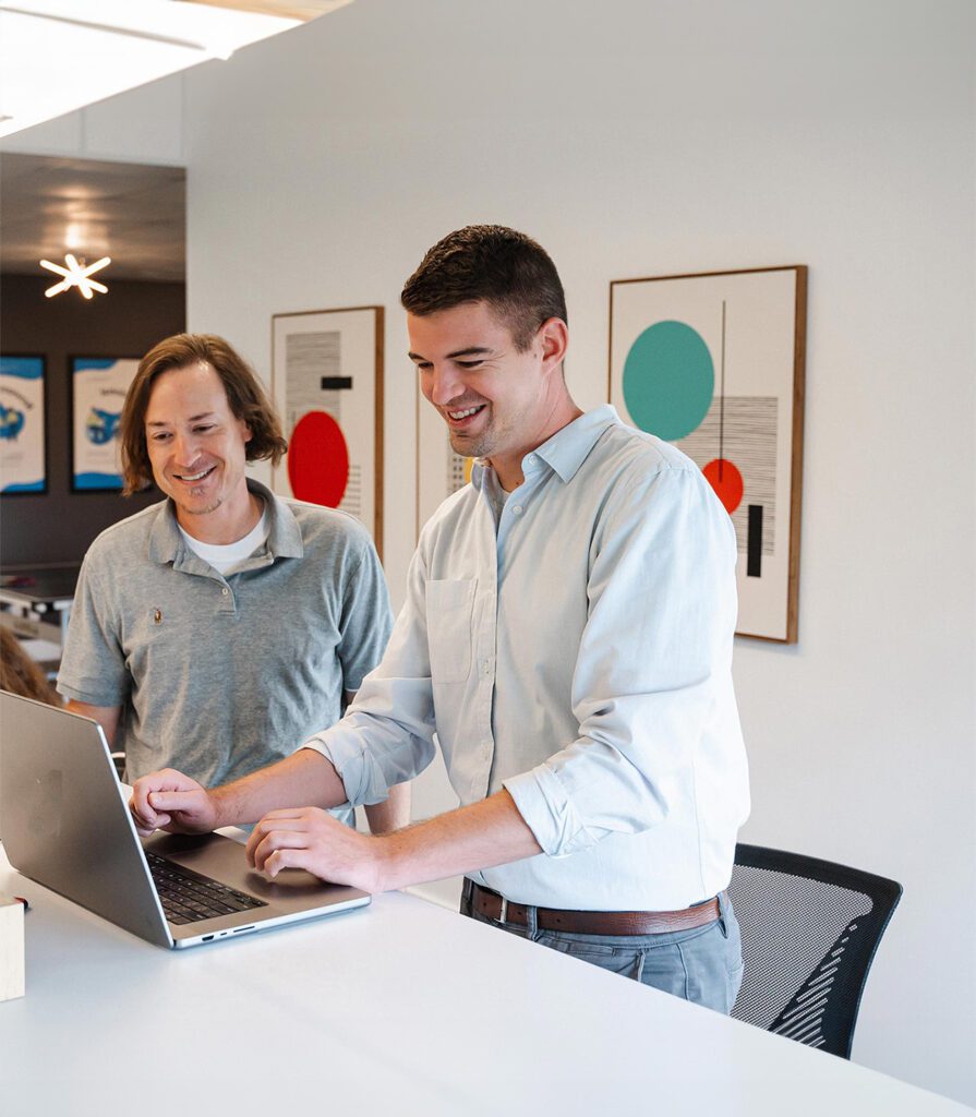 aaron-erich-desk-flipped TwoTone Creative team members collaborating on laptop, fostering client success and resourceful problem-solving.