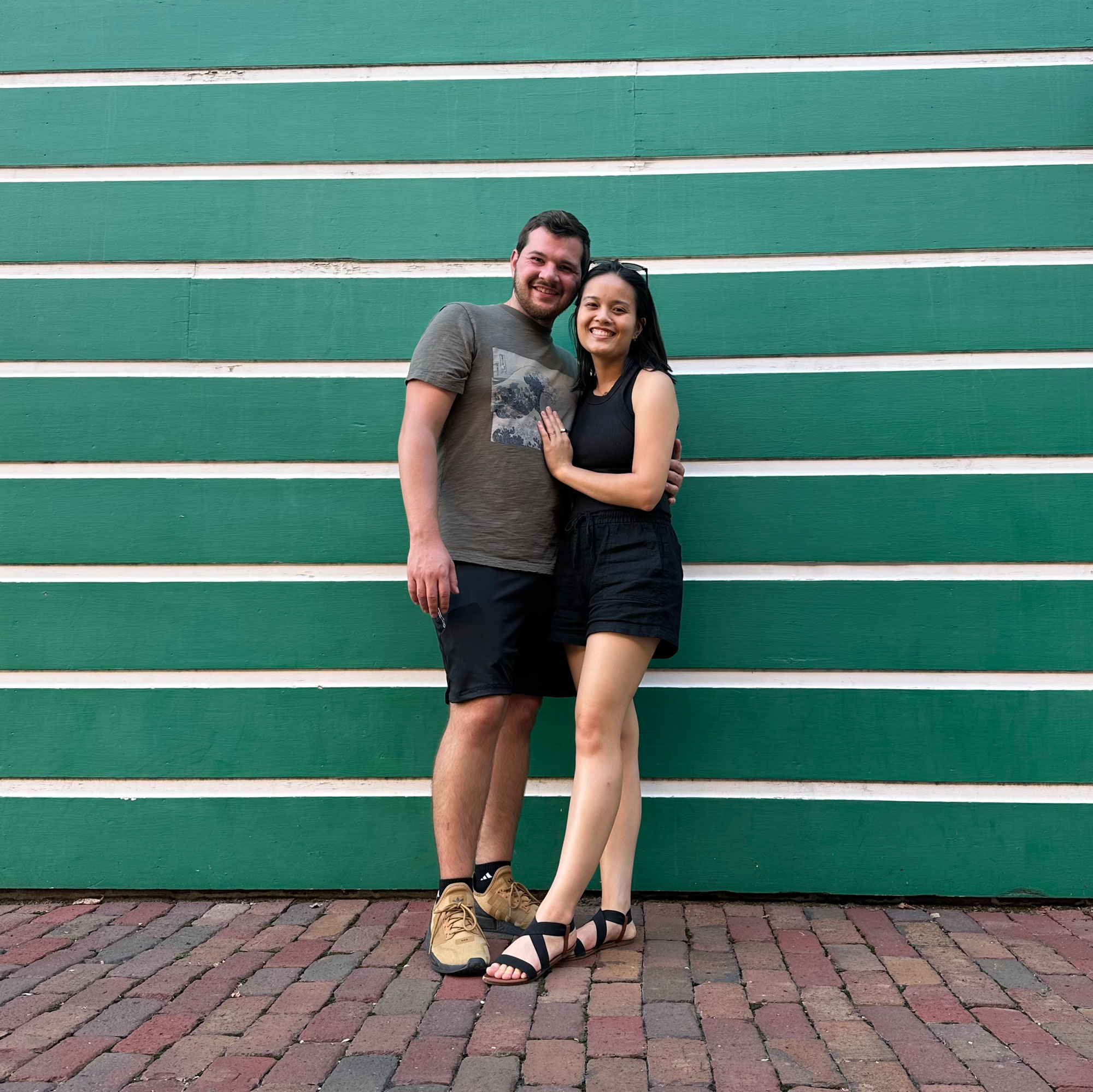 Sofia Dickens and her husband, smiling portrait against green striped wall.