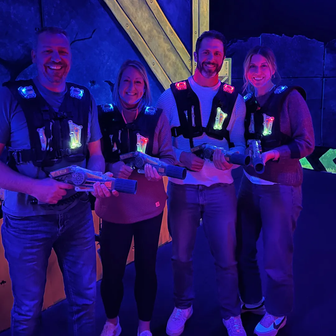 TwoTone Creative team members Terra, and colleagues smiling and playing laser tag.