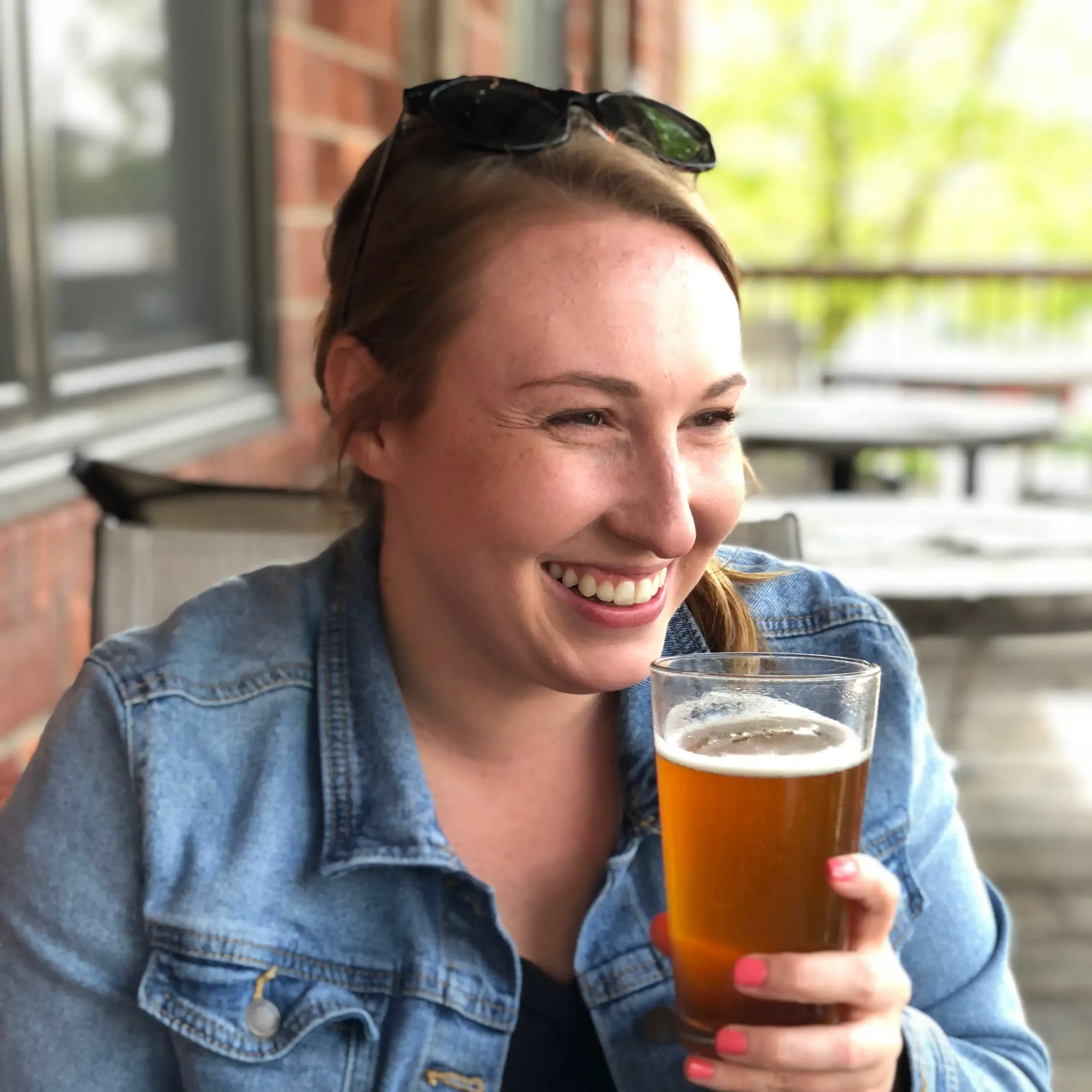 Lauren Parker smiling and holding a glass of beer outside a local brewery.