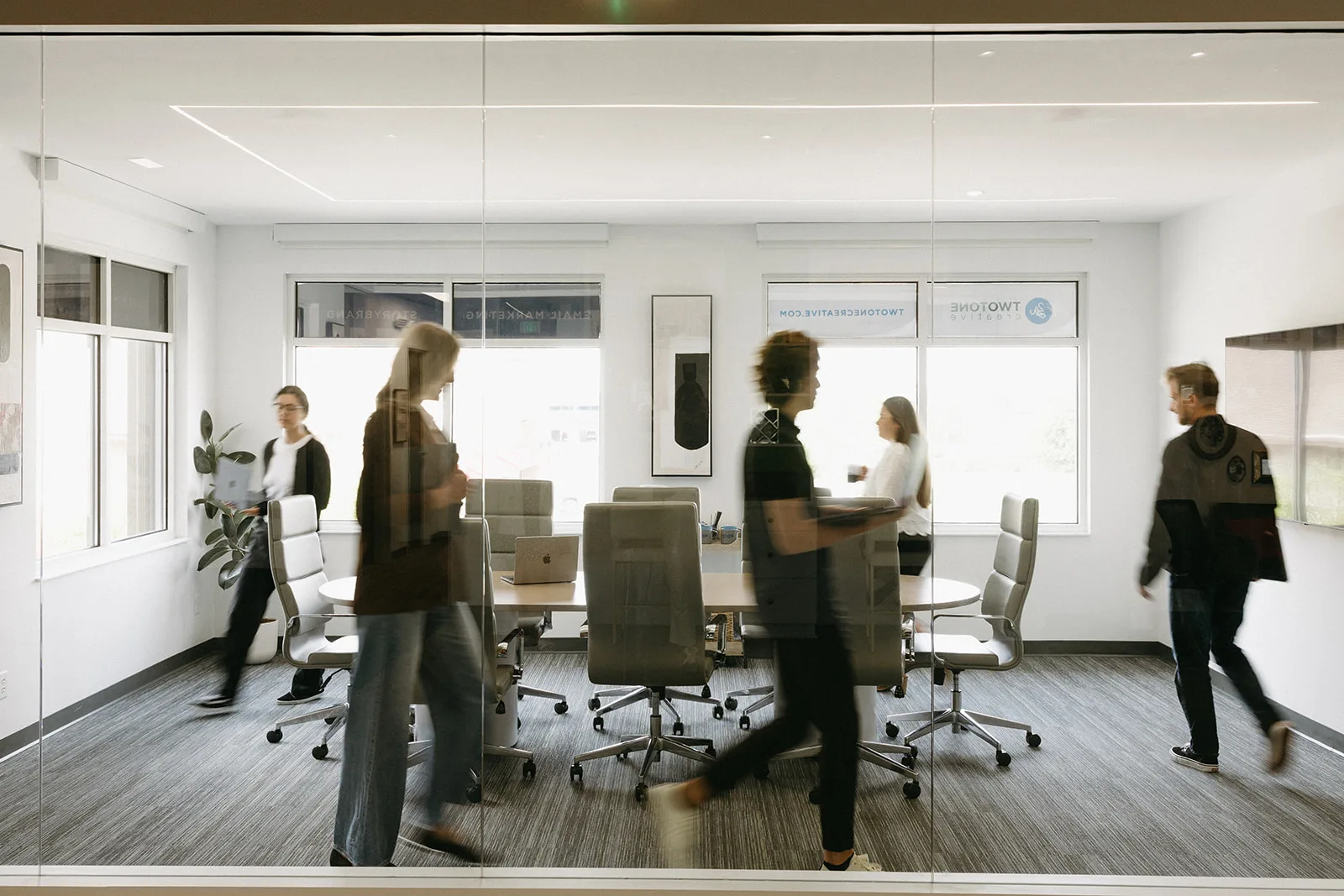 Bright, modern office space at TwoTone Creative with employees collaborating and moving between workstations.