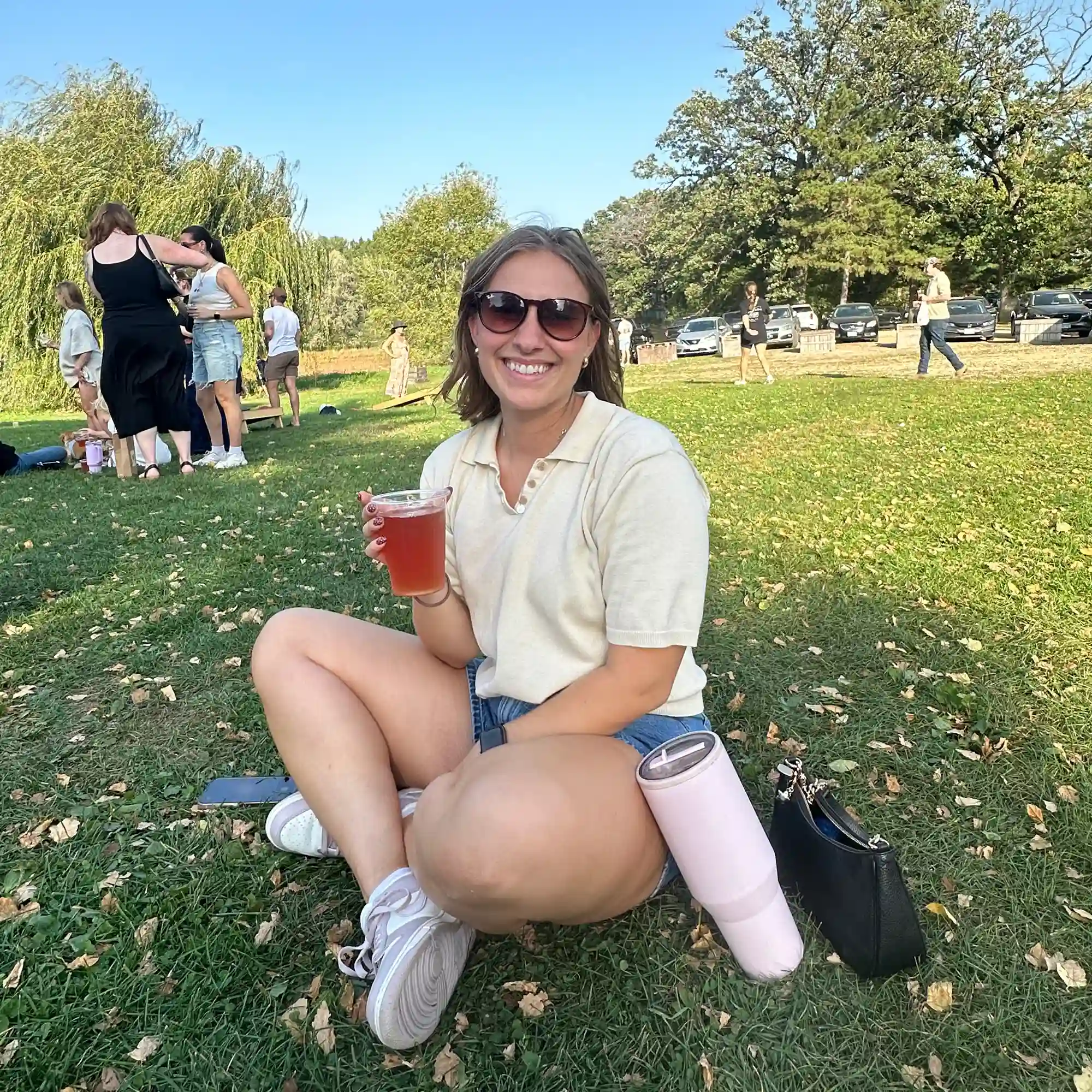 Molly Unick smiling and holding a drink outdoors, illustrating an active lifestyle and creative spirit.