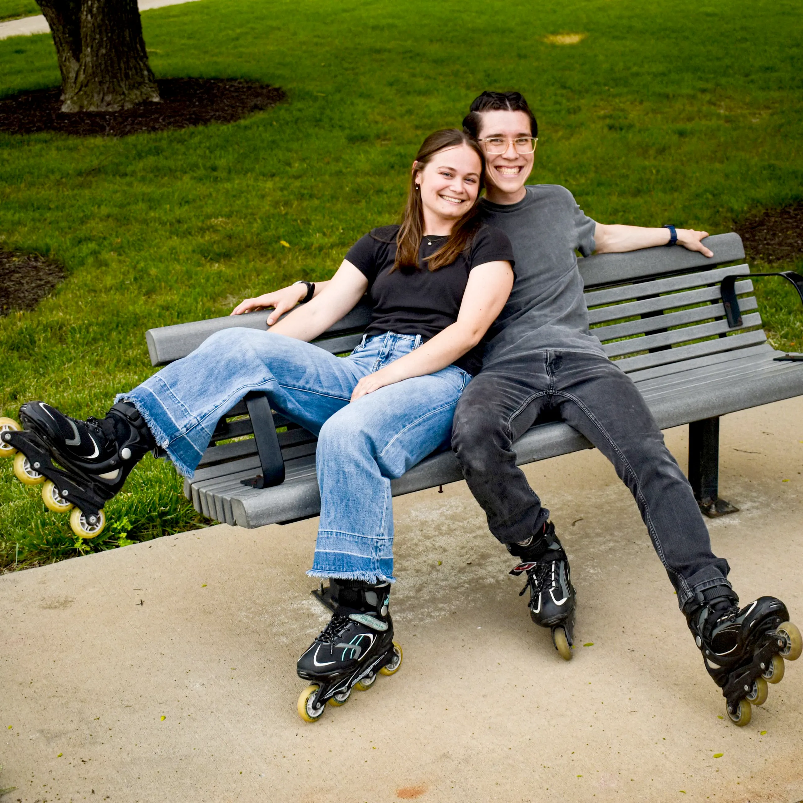 Emily Gibson and a companion relaxing on a park bench, inline skating.
