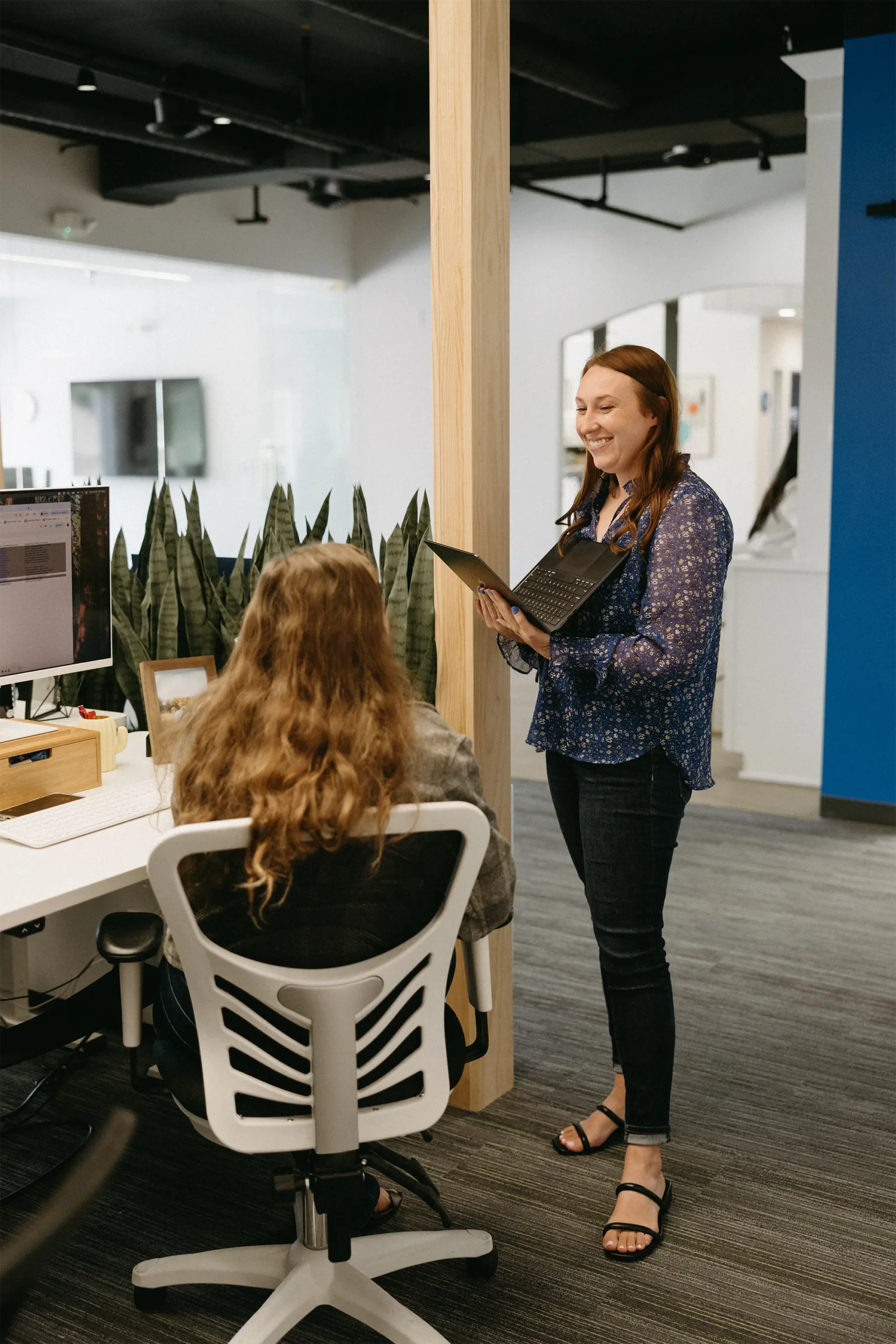 TwoTone Creative office scene: employee presenting to colleague, fostering teamwork and collaboration.