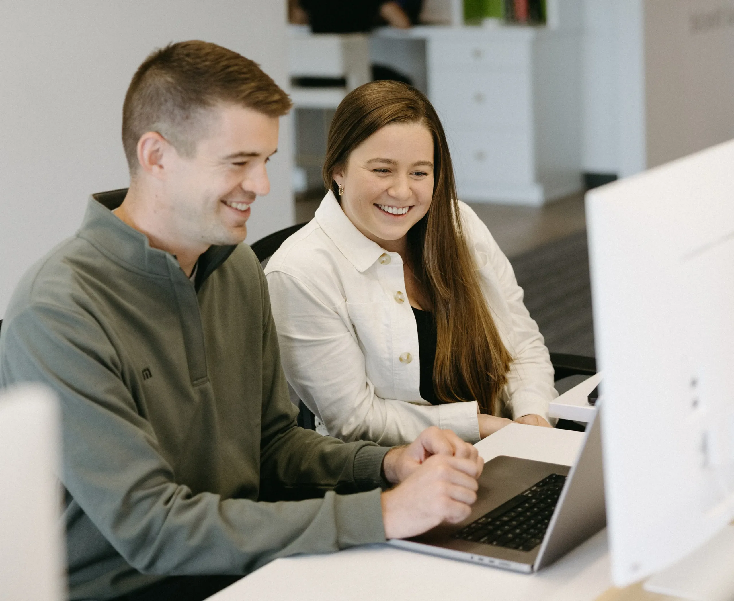 TwoTone Creative team members smiling and collaborating at a laptop.