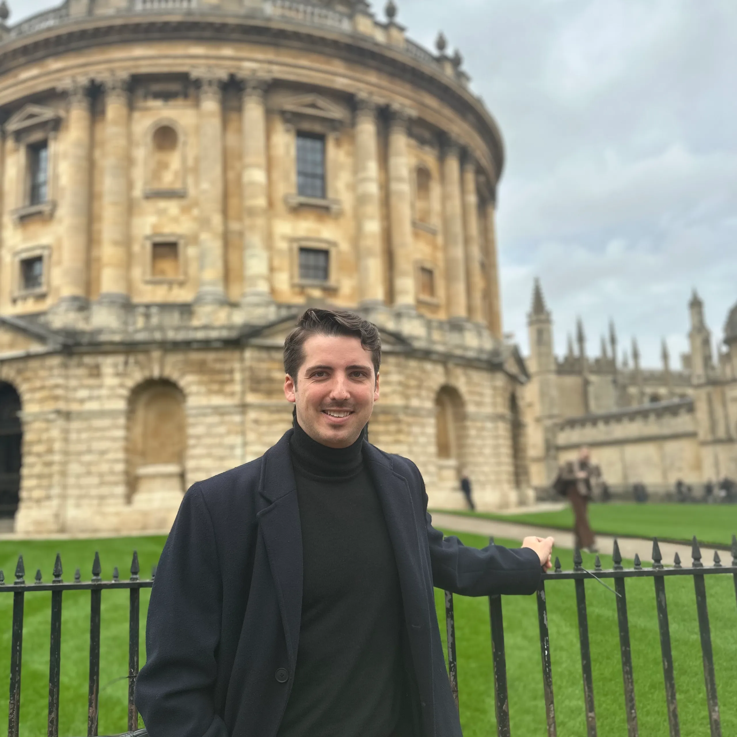 Cameron Blom in front of the University of Edinburgh building, showcasing academic background and perspective.